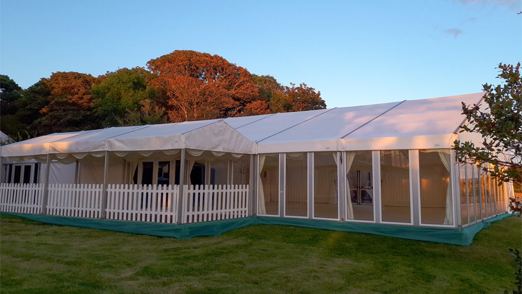 Interior of a wedding marquee with staged tables, cream linings, chandeliers and a feature starlight lining in the background