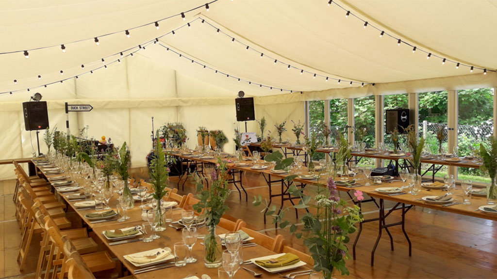 Interior of a marquee with tables running up and down and a unique party theme decorating the space