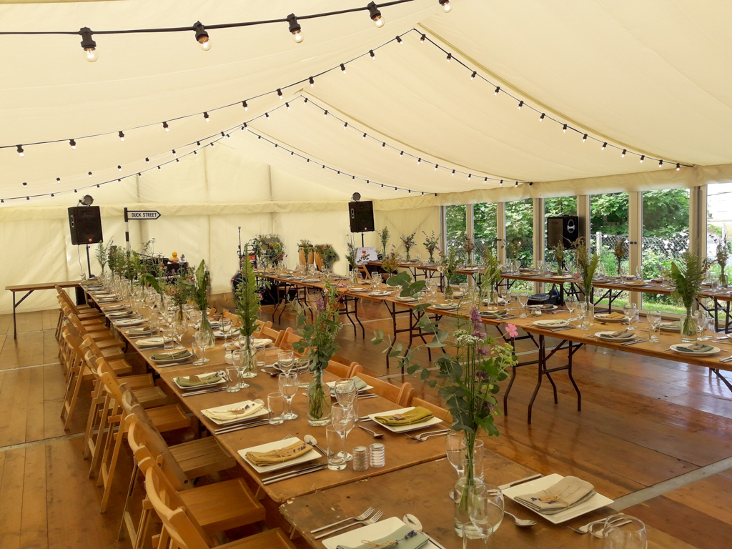 Interior of a marquee with tables running up and down and a unique party theme decorating the space