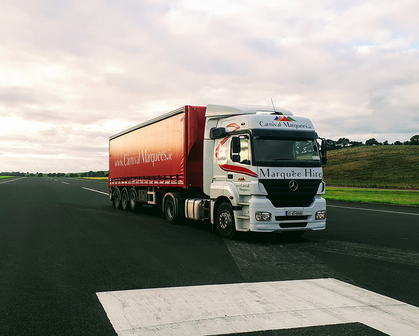 A Carnival Marquees branded truck and trailer parked on a runway