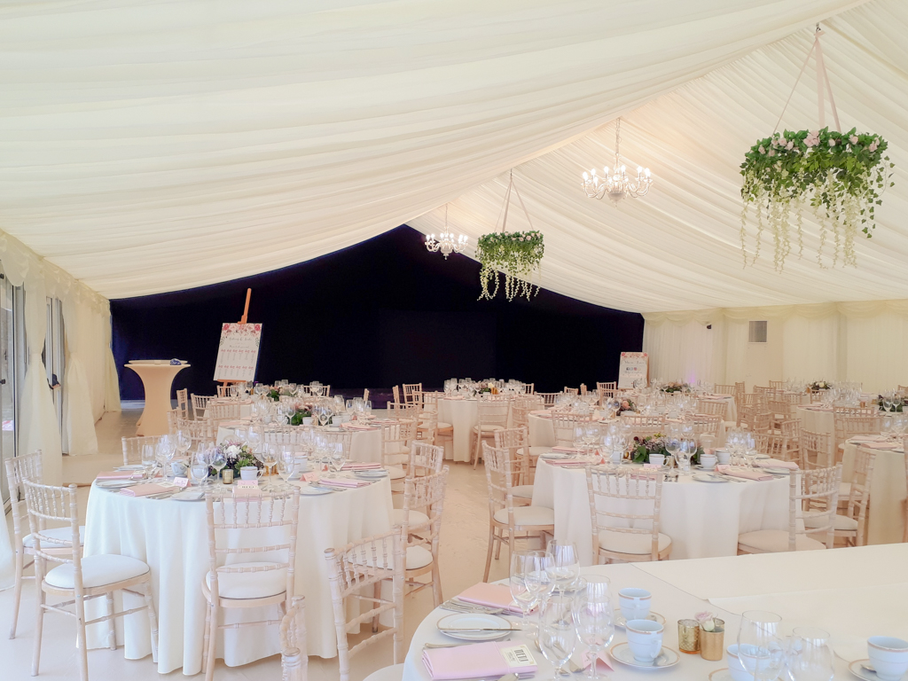 Interior of a wedding marquee with staged tables, cream linings, chandeliers and a feature starlight lining in the background